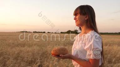 手里拿着美味的面包，把一个年轻漂亮的女人抱在麦田里。 一个女孩手里拿着的面包